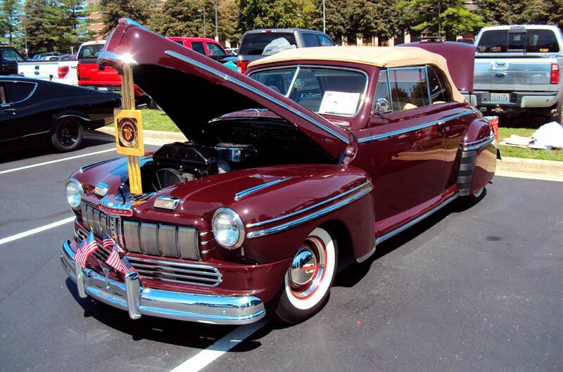 Front of a classic red Mercury with hood open in parking lot