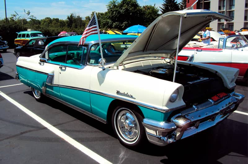 Front profile of a white and teal Pontiac Star Chief with hood open in parking lot