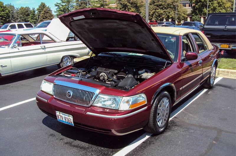 Front of a red Mercury with brown roof and hood open in parking lot