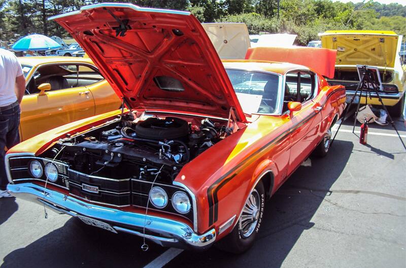 Front of a red Mercury with hood open in the parking lot