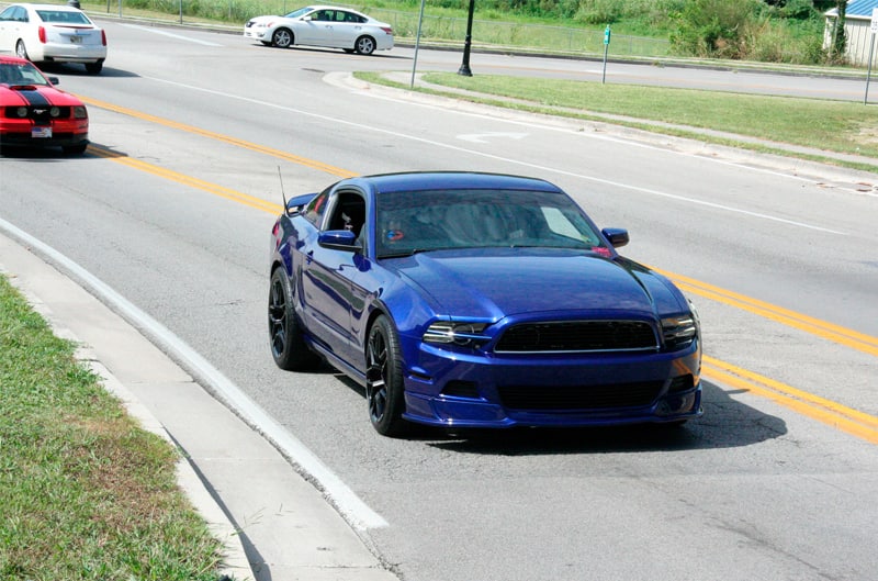 A blue Mustang driving down the road