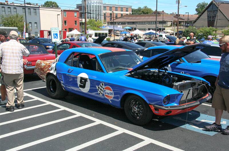 A classic blue Mustang on display with the hood up