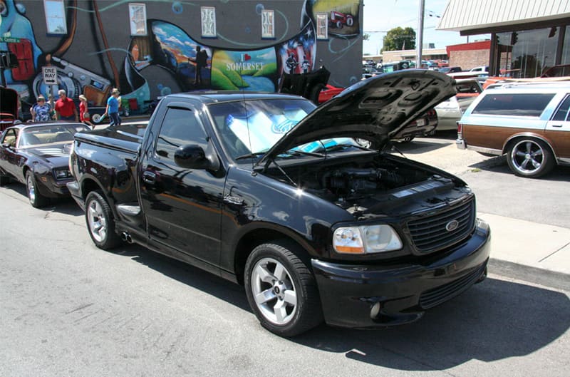 A classic black Ford truck on display with the hood up