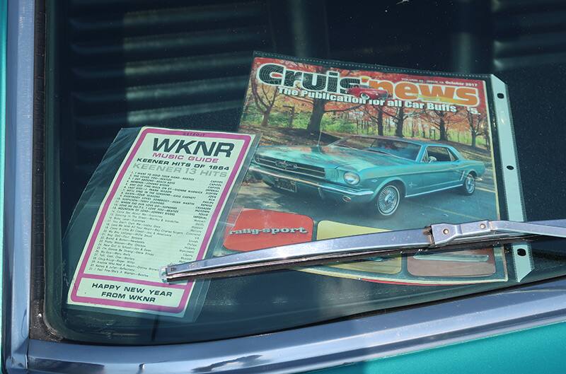 A car magazine and a list of hit songs on the windshield of a classic Mustang