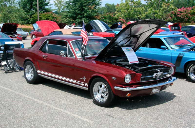 Front profile of a red Mustang with hood open in parking lot