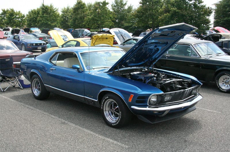 Front profile of a blue Mustang with hood open in parking lot