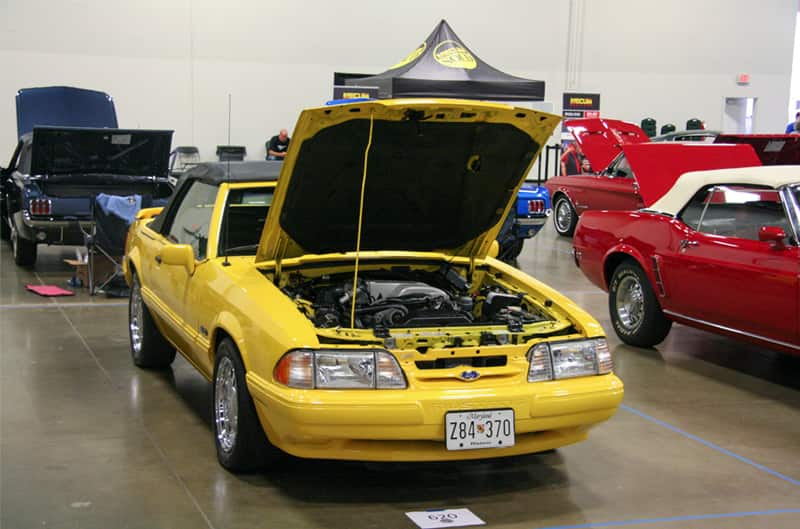 Front of a yellow Mustang with hood open in garage