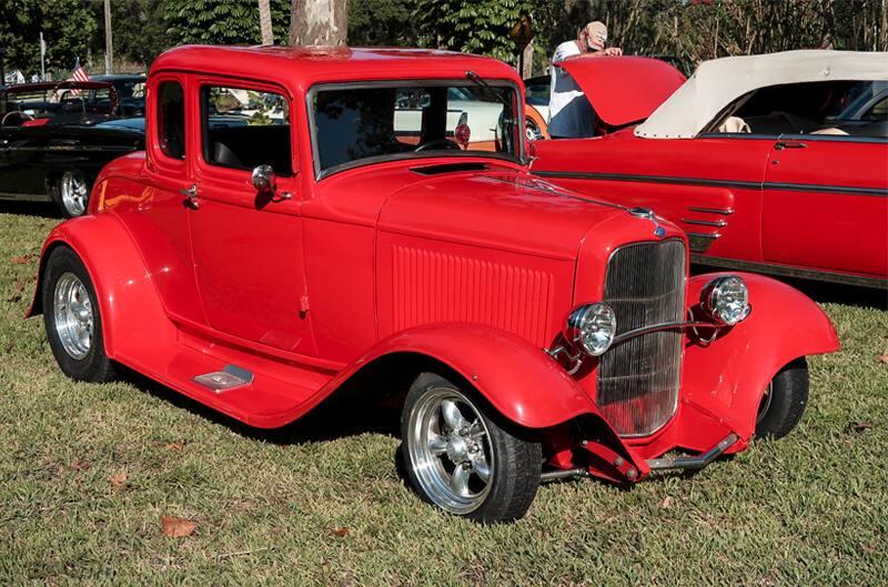 Front profile of a classic red Ford on the grass