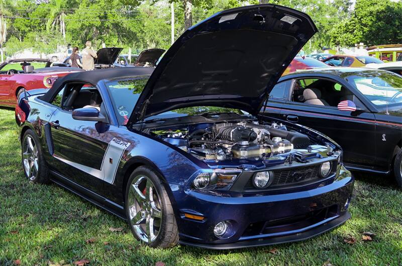 Front of a blue Mustang with hood open on the grass