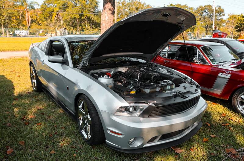 Front profile of a gray Mustang with hood open on the grass