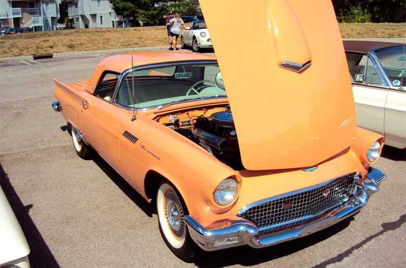 Front of an orange Thunderbird with hood open in parking lot