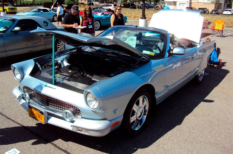 Front of a baby blue Thunderbird convertible with hood and trunk open in parking lot