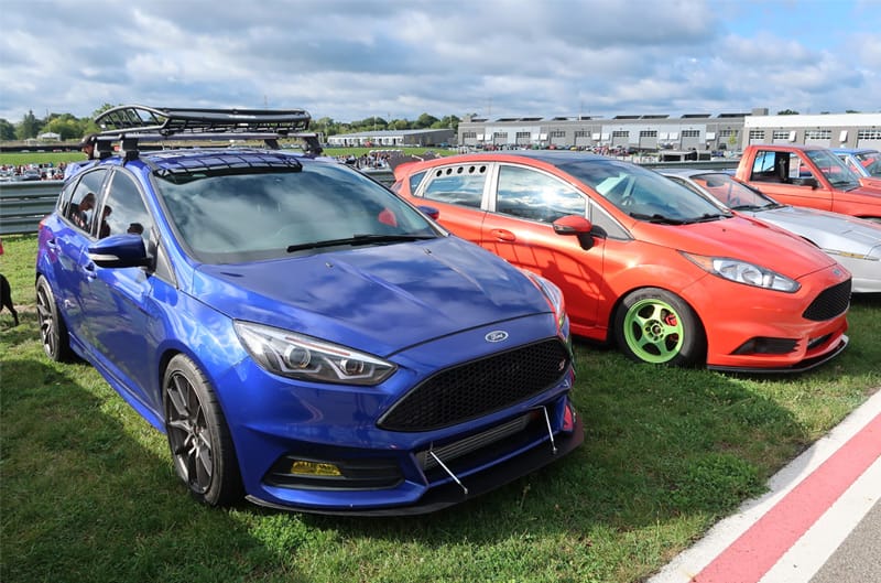 A blue and a red Focus parked on the grass