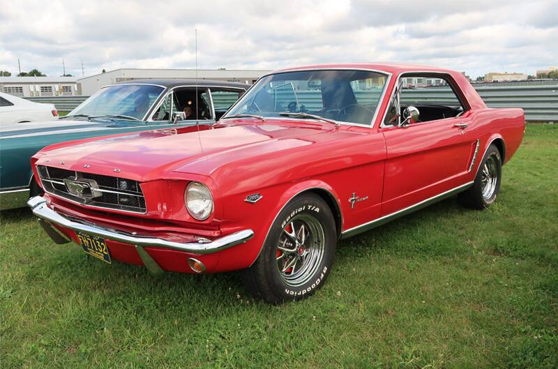 Front profile of a red Mustang parked on grass