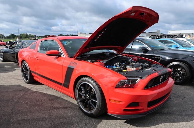 Front profile of a red Mustang Boss 302 with hood open in the parking lot