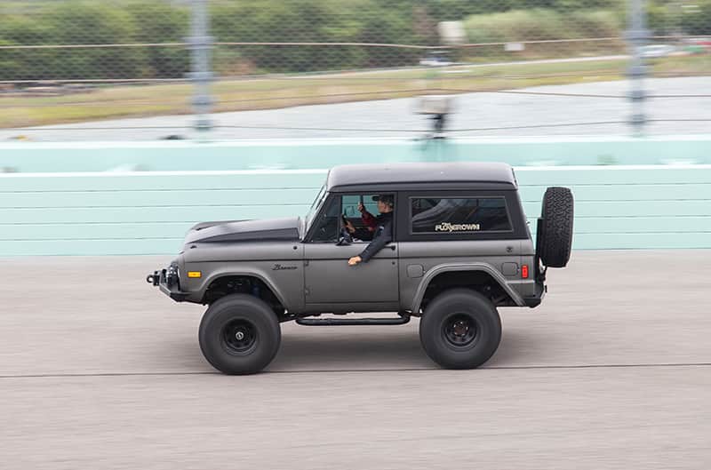 A side view of a grey Bronco zooming down the track