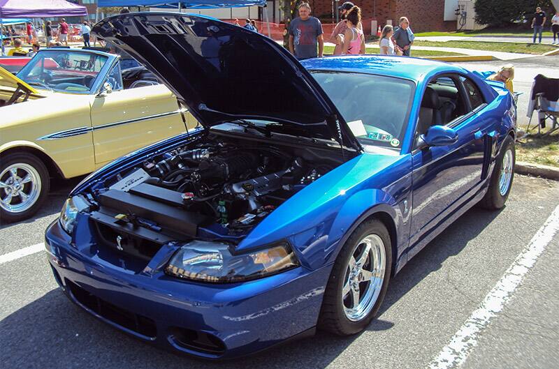 A blue Mustang on display with the hood up