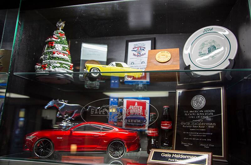 Display case of a red Shelby Mustang and various other Ford items