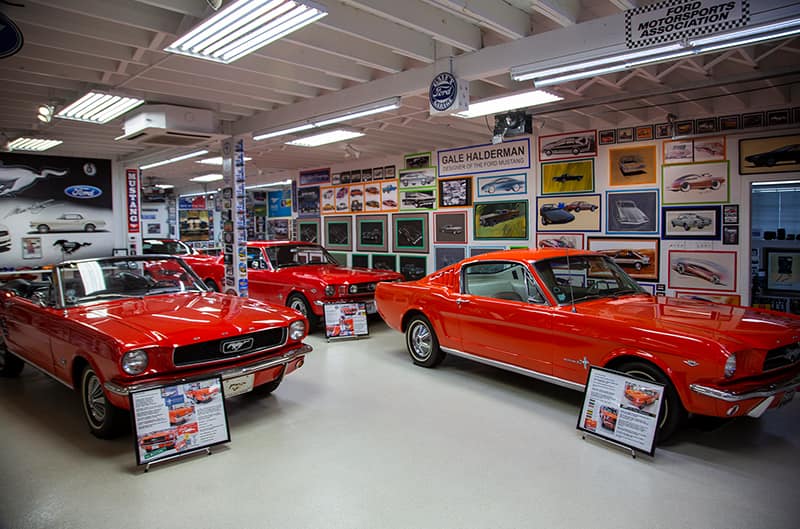 Three red Mustangs parked inside garage
