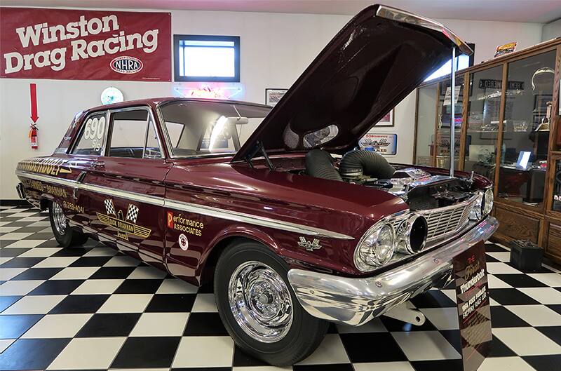 Front profile of a burgundy Thunderbolt with hood open in a garage