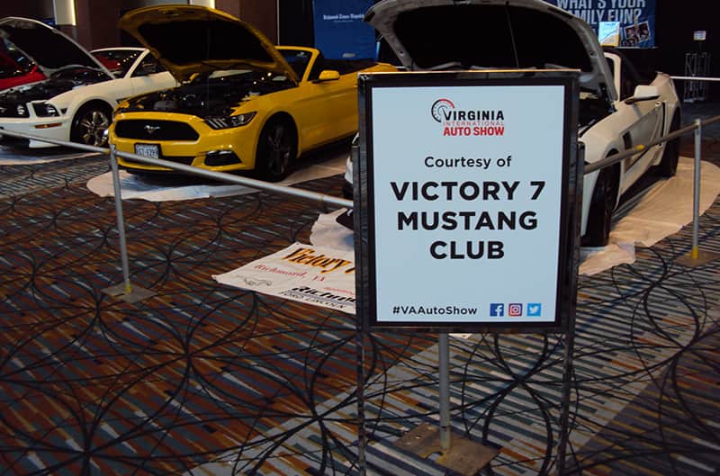 Victory 7 Mustang Club sign in front of various Mustangs on display