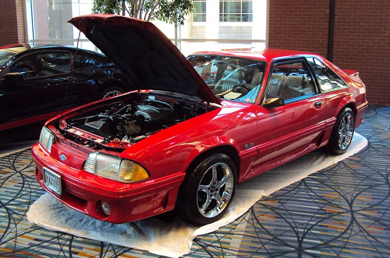 Front profile of a red Mustang with hood open on display