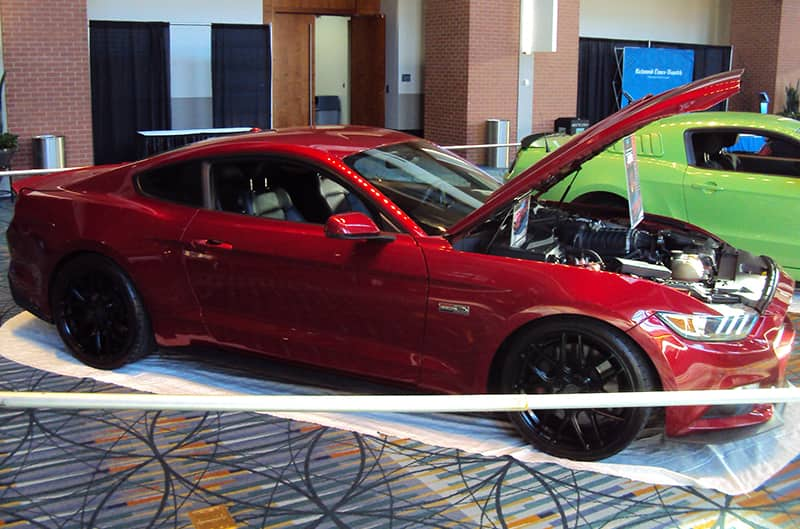 Profile of a red Mustang with hood open on display