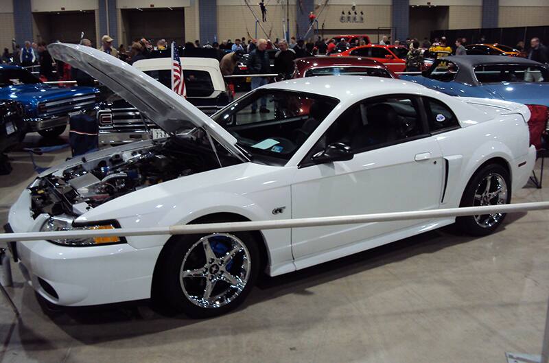 Profile of a white Mustang GT with hood open on display