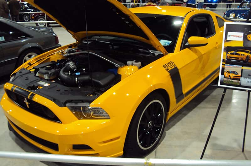 Front profile of a yellow Mustang Boss 302 with black stripes and open hood
