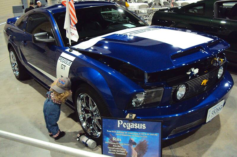 Front profile of a blue Pegasus GT with white stripe on open hood on display