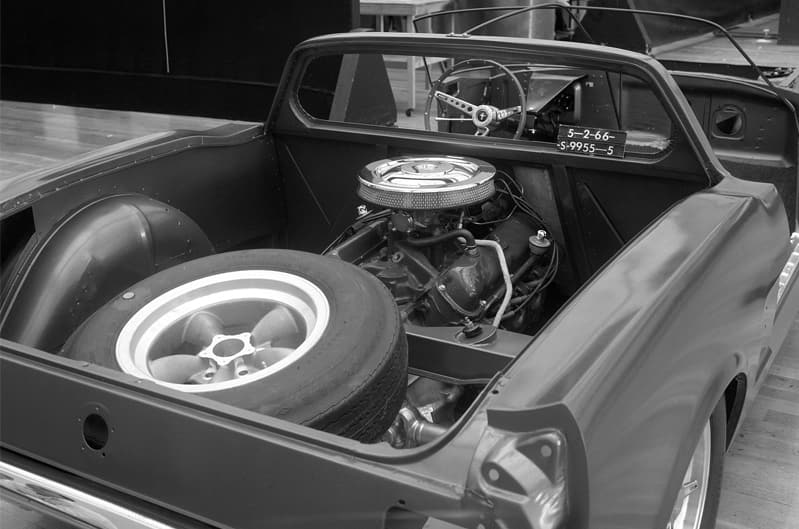 A closeup of the engine and spare tire under the hood of a Mustang