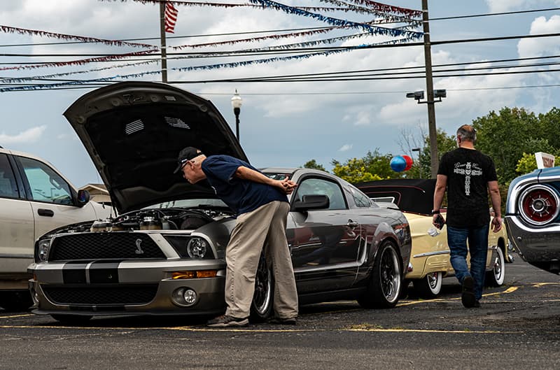 2007 GT500 mustang with man peering into engine bay