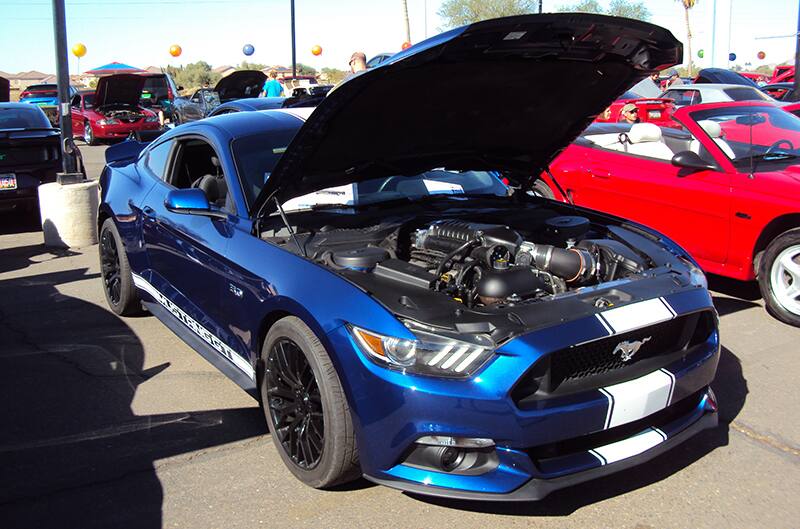 Front of brown Mustang convertible wit hood open in parking lot