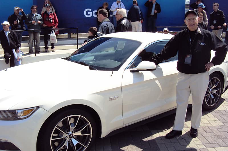 Gale Halderman standing by White S550 Mustang
