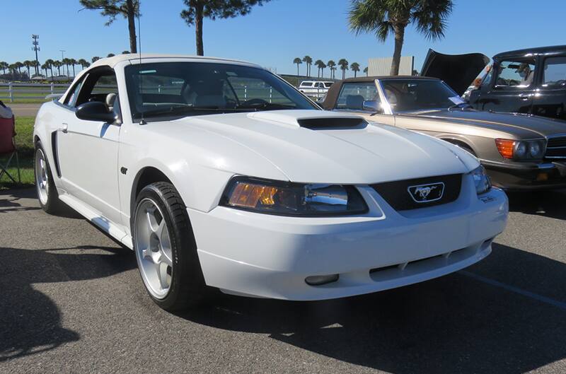 White 2000s Mustang with Cobra R wheels