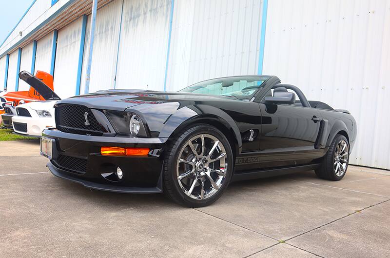 Black Shelby GT500 Mustang with chrome wheels at car show