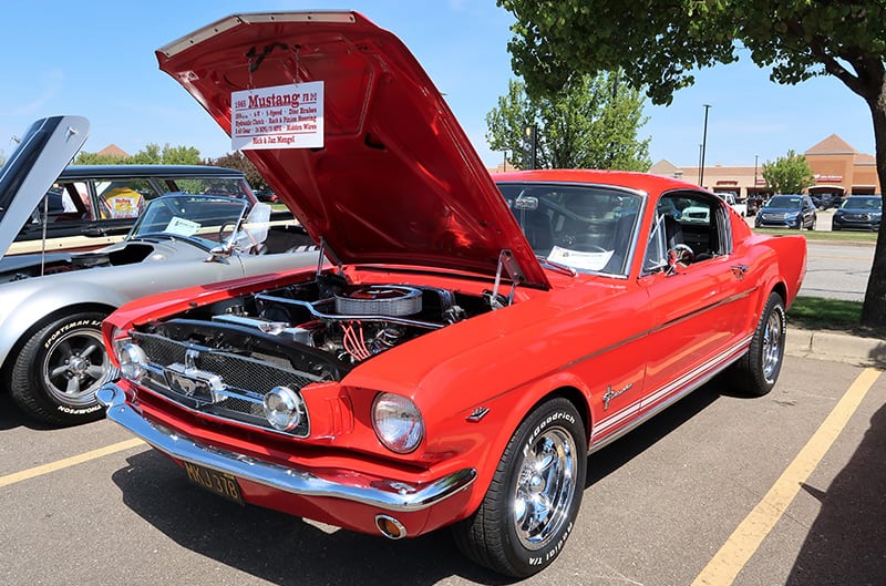 Red 1960s Mustang with hood open at show