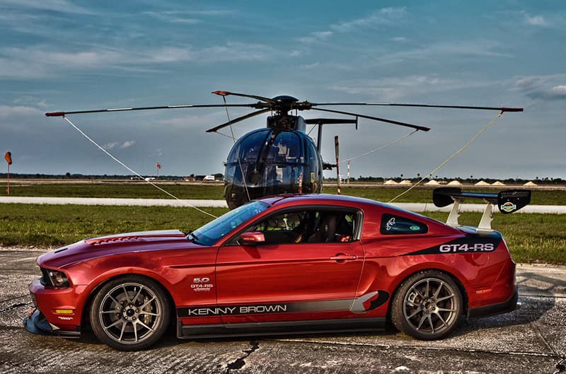 Red side shot of S197 Mustang with helicopter in background