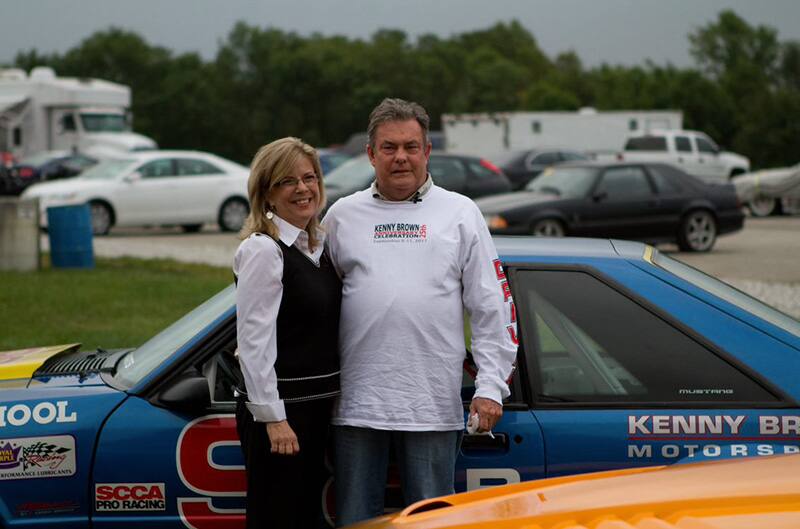 kenny standing with woman in front of mustang