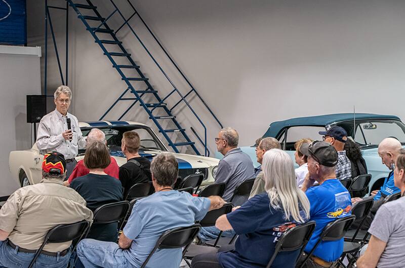 Man speaking to crowd inside Museum