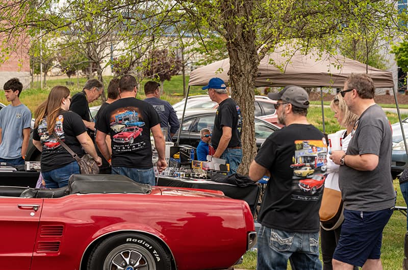 Group of people standing around mustangs