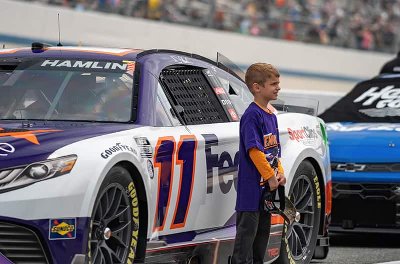 young boy standing by number 11 fedex mustang