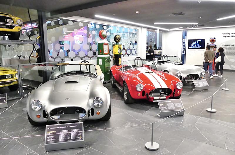 Several shelby cobras on display inside