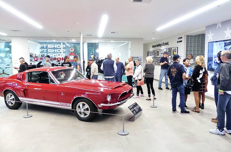 First gen Shelby mustang in red with people standing around