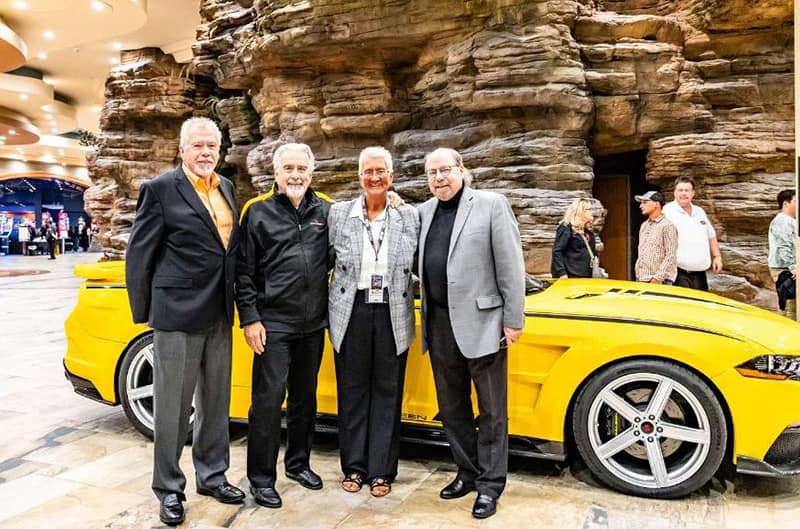 Group of men standing with yellow mustang