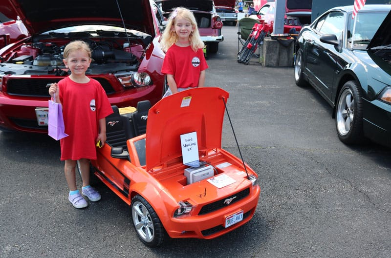 kids next to red battery mustang