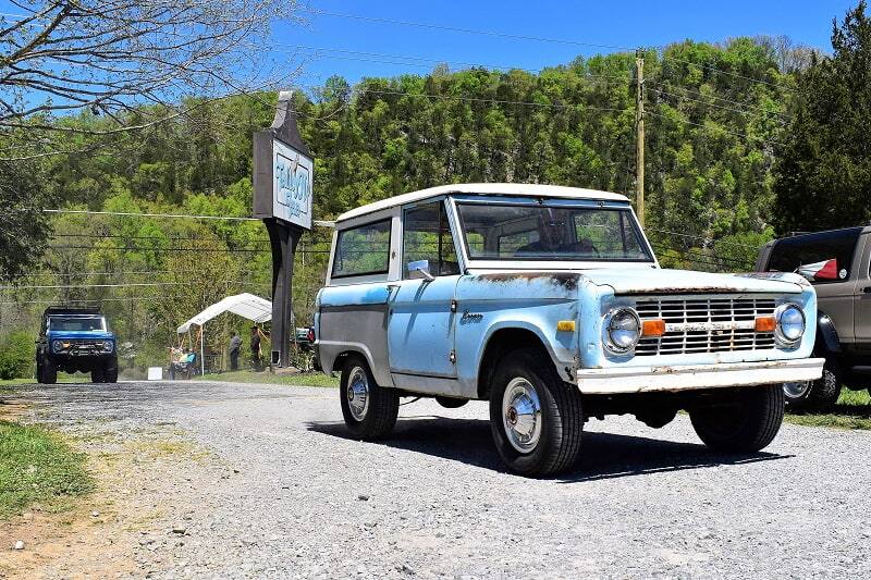 Light blue, white rusted Bronco on dirt road