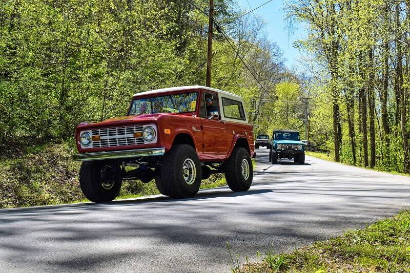 Red Bronco on road with Broncos in the back