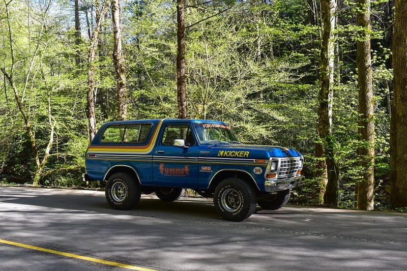 Profile of blue Bronco on forest road