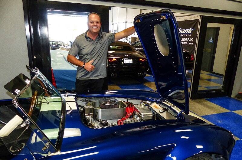 Lance Strander holding the hood up of a blue Shelby Cobra